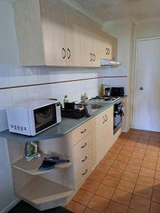 a kitchen with a microwave on top of a counter at Large studio balcony, spa & pool in Brisbane