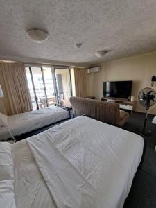 a hotel room with a bed and a television at Large studio balcony, spa & pool in Brisbane