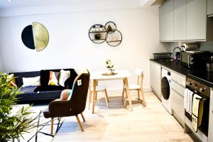 a kitchen and living room with a table and a couch at Fully Furnished 2 Bed Luxury Apartment with Free Parking,10 mins drive to Wembley Stadium, 5 mins drive to Brent Cross Shopping Mall & Free Parking onsite in Golders Green