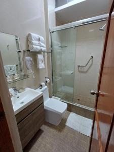a bathroom with a shower and a toilet and a sink at Arena Hostal in Paracas