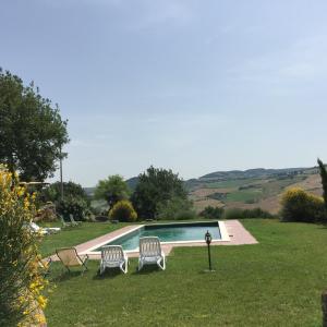 una piscina en un patio con 2 sillas en Villa Fonte all'Oppio con area piscina recintata, en Pienza