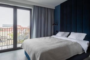 a bedroom with a large bed and a balcony at AVAPATRS Apartament BLUE in Jastarnia