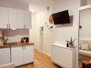 eine Küche mit weißen Schränken und einem TV an der Wand in der Unterkunft Mignon petit studio 16m2 in Les Lilas
