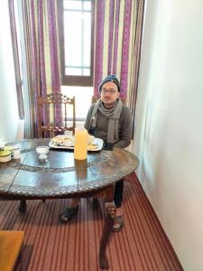 a woman sitting at a table in a room at Sea Green Guest House in Srinagar