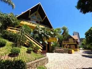 uma casa amarela com um telhado preto em Pousada Do Chalé em Bento Gonçalves