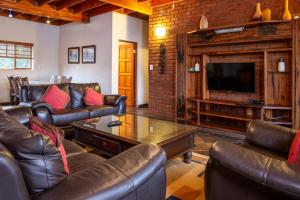 a living room with leather furniture and a flat screen tv at Sondela Nature Reserve & Spa Makhato Lodges in Bela-Bela