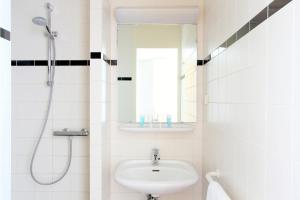 een witte badkamer met een wastafel en een douche bij Bastion Hotel Heerlen in Heerlen
