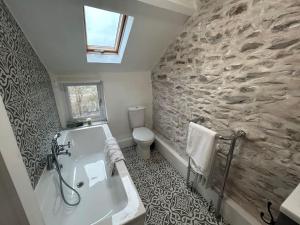 uma casa de banho com um lavatório branco e uma parede de pedra em Little Cottage, Big Character em Pontypridd