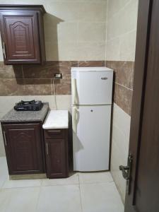 uma cozinha com um frigorífico branco e armários de madeira em الشقة العائلية الحديثة em Amã
