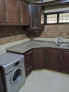 uma cozinha com uma máquina de lavar roupa e um lavatório em الشقة العائلية الحديثة em Amã