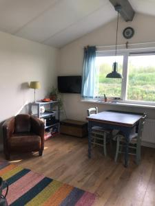 - un salon avec une table et une chaise dans l'établissement Rosa's zonnige huisje bij duinen bos en strand, à Warmenhuizen