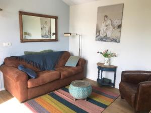 ein Wohnzimmer mit einem braunen Sofa und einem Spiegel in der Unterkunft Rosa's zonnige huisje bij duinen bos en strand in Warmenhuizen