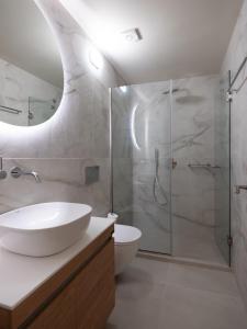 ein Bad mit einem Waschbecken und einer Glasdusche in der Unterkunft Casa Del Centro Storico,By IdealStay Experience in Iraklio