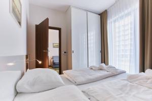 1 Schlafzimmer mit 2 weißen Betten und einem Spiegel in der Unterkunft Apartamenty Świnoujście - Aleja Baltic Park Molo in Świnoujście