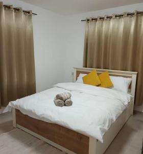 a bedroom with a bed with white sheets and yellow pillows at Sraya Hostel_Big in Majdal Shams