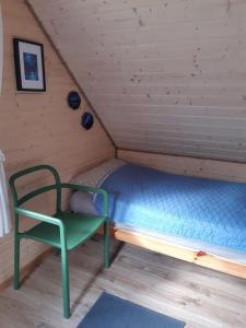 a bed in a room with a green chair at Qubalonka Saunarium bis Bory Tucholskie in Karsin