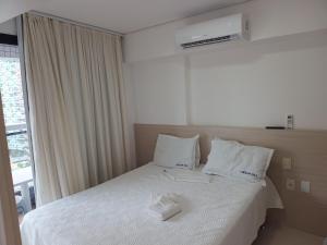 um quarto com uma cama com lençóis brancos e uma janela em Apartamento Mobiliado Meireles Fortaleza Landscape Beira-Mar em Fortaleza