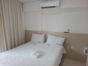 um quarto com uma cama com lençóis brancos e almofadas em Apartamento Mobiliado Meireles Fortaleza Landscape Beira-Mar em Fortaleza