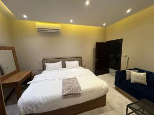 1 dormitorio con 1 cama y 1 sofá azul en كمباوند السليمانية en Riad
