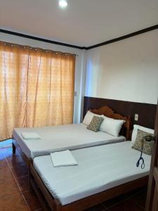 1 dormitorio con 2 camas y ventana en VILLA LOURDES RESORT en Boracay