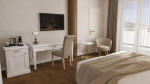 プラハにあるHotel Savoy Pragueのベッド、デスク、椅子が備わるホテルルームです。