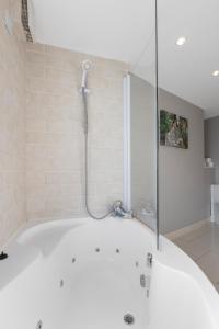 a shower in a bathroom with a tub at 55 North Apartments Portrush in Portrush