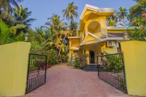 a yellow house with a gate and a driveway at Belleville - A Peaceful Holiday Home in Madgaon