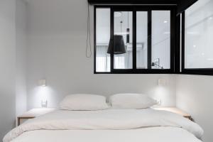 a white bedroom with a large bed and a window at #Nereids Apts by halu! Apartments in Thessaloniki