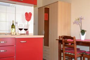 una cucina con armadi rossi e un tavolo con bicchieri da vino di Apartments Kodzoman a Brodarica