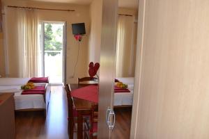 a room with two beds and a table and a window at Apartments Kodzoman in Brodarica