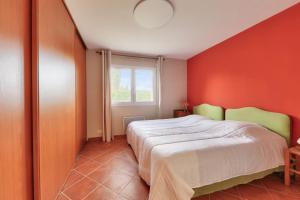 a bedroom with a bed with an orange wall at Maison 4 chambres - Tour du Parc in Le Tour-du-Parc