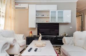 a living room with white furniture and a tv at Beach Heaven Apartments in Durrës