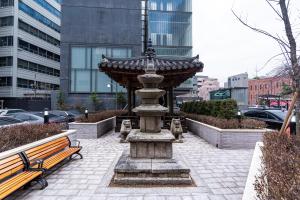 首爾的住宿－The Prima Hotel Jongno，一座有两长椅的城市中的石头喷泉