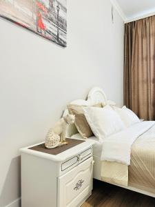 1 dormitorio con 1 cama blanca y mesita de noche en Grand champion en Astaná