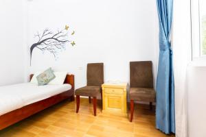a room with a bed and two chairs and a table at Cat Ba Countryside Homestay in Cat Ba