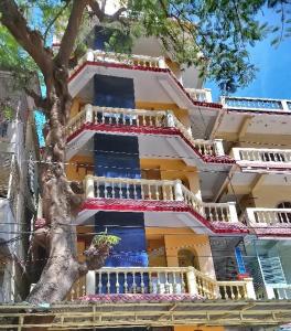 a large building with a tree in front of it at Casa di Mara in Puttaparthi