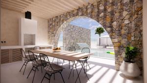 une salle à manger avec une table et un mur en pierre dans l'établissement Kallithea Luxury Villas #4, à Koskinou