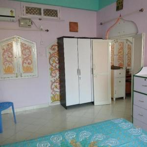 a bedroom with pink walls and white cabinets and a bed at Casa di Mara in Puttaparthi