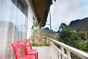 two red chairs sitting on a balcony with flowers at Cat Ba Countryside Homestay in Cat Ba