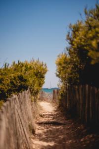 a dirt road next to a fence and the ocean at Salines in Hyères