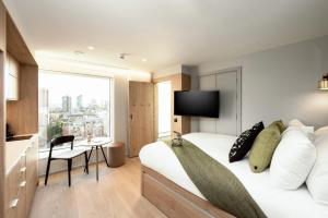 a hotel room with a bed and a large window at Wilde Aparthotels London Aldgate Tower Bridge in London