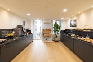 a large kitchen with black cabinets and a wooden floor at Fred Hotel Zürich Hauptbahnhof in Zurich