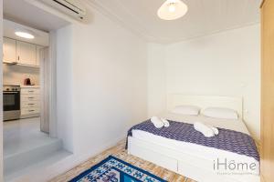 a white bedroom with a bed and a kitchen at Kokkari's Destiny - at the heart of the City Center in Kokkari