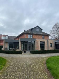 a large brick house with a stone driveway at Velo Villa in Achel