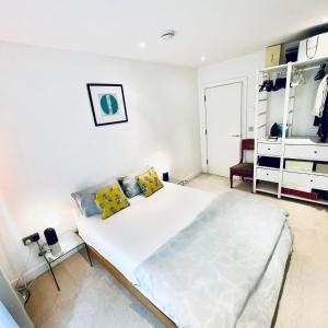 a white bedroom with a large bed and a dresser at Central Room In Shoreditch in London