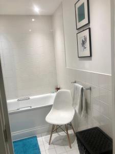 a white bathroom with a white tub and a white chair at Central Room In Shoreditch in London
