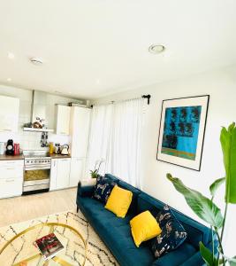 uma sala de estar com um sofá azul e almofadas amarelas em Central Room In Shoreditch em Londres