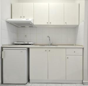 uma cozinha com armários brancos e um lavatório em PERASMA ROOMS em Leptokarya