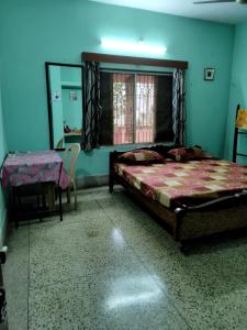 Schlafzimmer mit einem Bett, einem Tisch und einem Spiegel in der Unterkunft Ashiyana in Bhubaneshwar