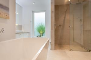 a white bathroom with a shower and a tub at Bäum Hüs A in Westerland (Sylt)